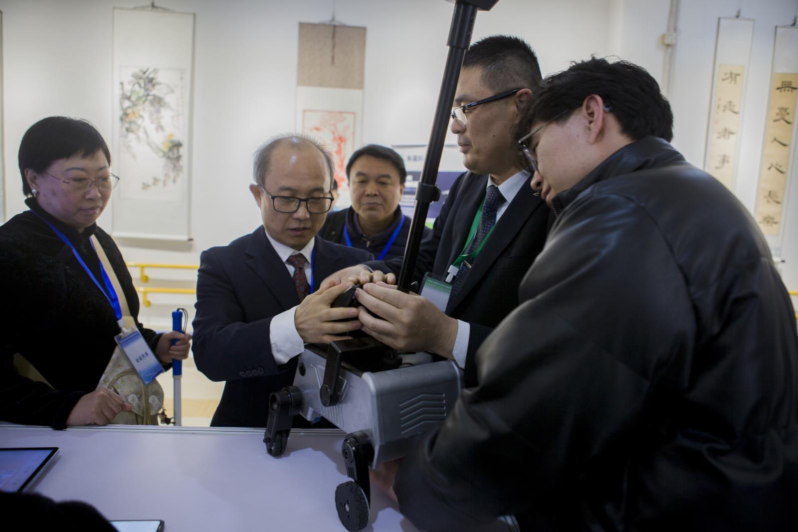 图为中国盲协主席李庆忠抚摸感受助理机器人外观.jpg